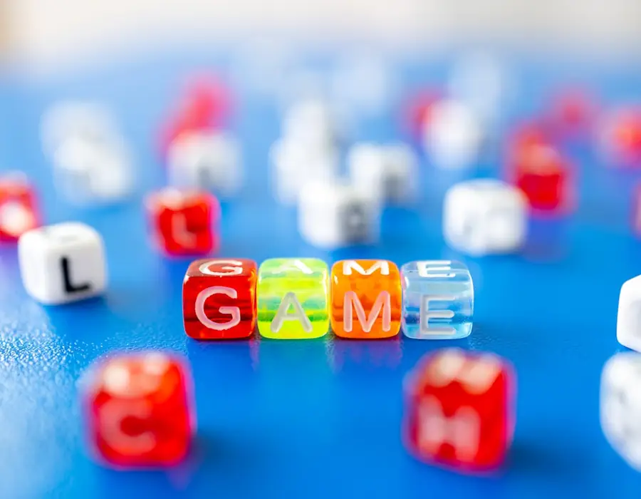 Peças coloridas de letras a soletrar a palavra GAME sobre fundo azul
